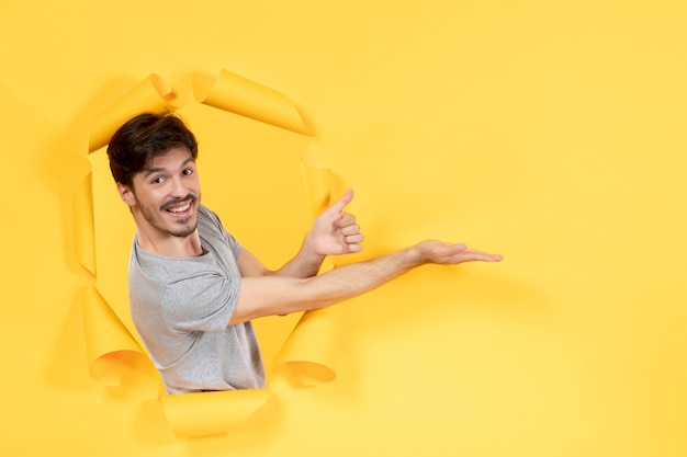 junger Mann auf zerrissenem gelbem Papierhintergrund hübscher Gesichtstyp indoor