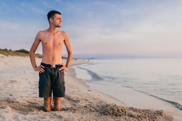 Foto junger mann, der im loch am strand steht