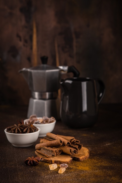 Kaffeekanne mit Gewürzen auf braunem Hintergrund.