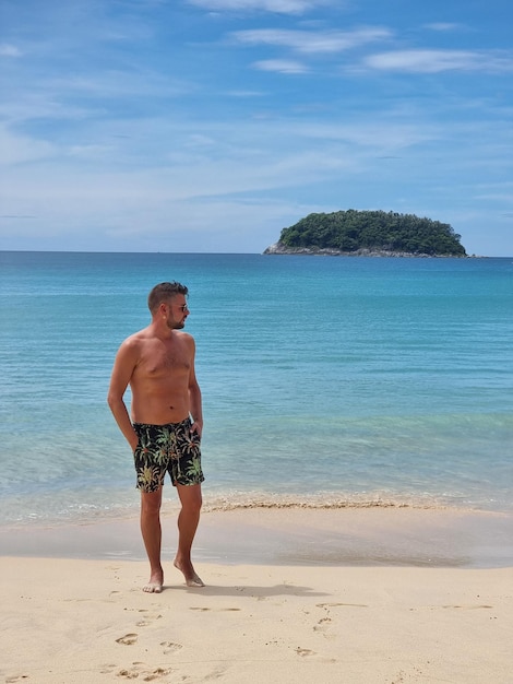 Foto kata strand phuket thailand junger mann geht am strand in schwimmshorts in thailand