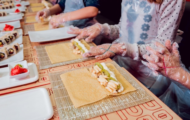 Kinder bereiten Sushi und Brötchen zu. Meisterklasse-Restaurant.