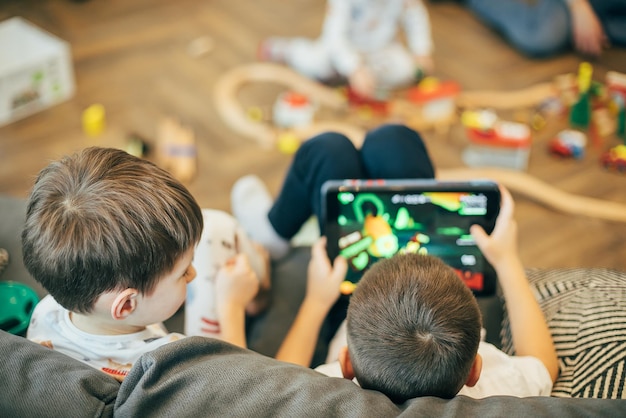 Foto kleine jungs mit tablet-pc sitzen auf dem sofa im wohnzimmer