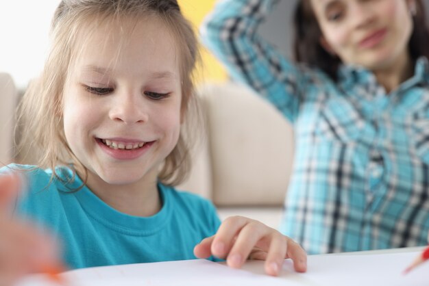 Kleines Mädchen zeichnet auf Papier neben Mutter