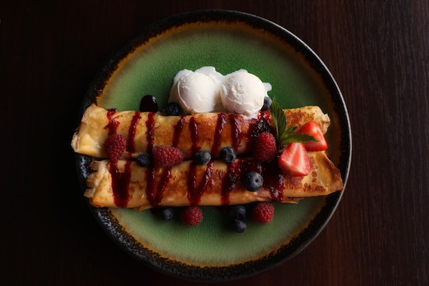 Foto köstliche pfannkuchen mit frischen beeren und eiscreme auf draufsicht des holztischs