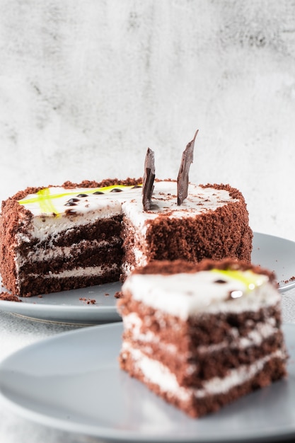 Köstlicher Schokoladenkuchen mit weißer Kokoscreme auf Teller auf Tisch auf Marmorhintergrund. Tapete für Konditorei oder Cafémenü. Vertikale.