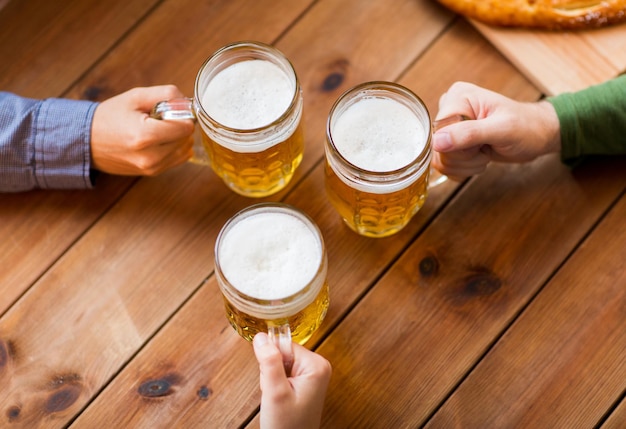 Foto konzept für menschen, freizeit und getränke - nahaufnahme männlicher hände mit bierkrügen in bar oder kneipe