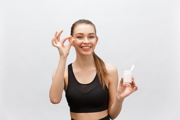 Lächelnde blonde Sportfrau, die Flasche Medizin hält