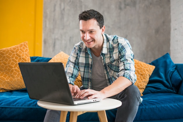 Lächelnder Mann, der zu Hause Laptop verwendet