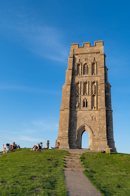 Foto landschaftsfoto von touristen, die auf dem gipfel von glastonbury tor in somerset sitzen