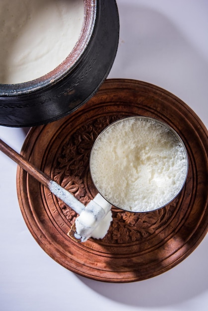 Lassi doce indiano feito de leite, requeijão, açúcar e sal misturado com cubos de gelo, servido em um copo de aço jumbo, preparado em panela de barro tradicional