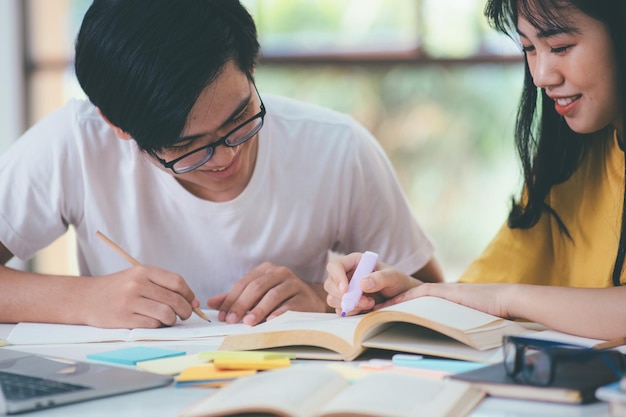 Foto lernbildung und schulkonzept junge frau und mann, die für einen test oder eine prüfung studieren tutor bücher mit freunden der campus junger studenten hilft freunden, aufzuholen und zu lernen