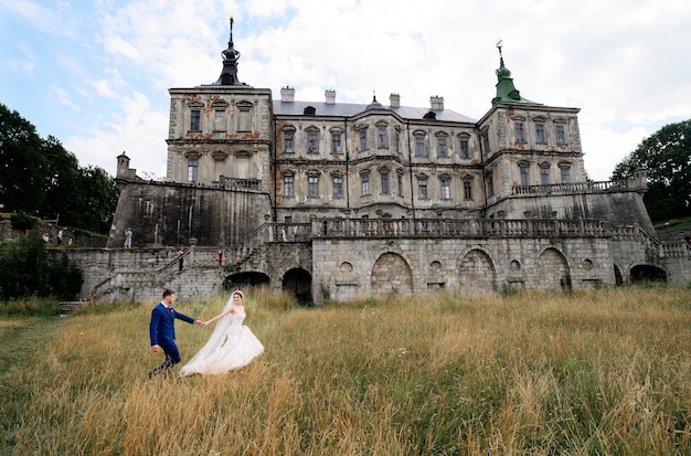 Lindo casal de noivos coloca antes de um velho castelo em ruínas