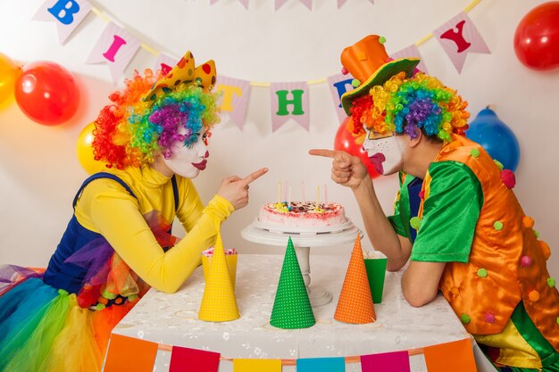 Foto lustige emotionale clowns auf der party können den kuchen nicht teilen