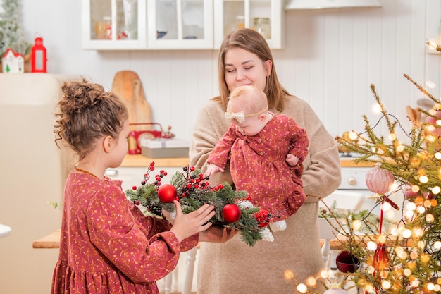 Mãe de família feliz com crianças brincando considere presentes de natal no interior decorado para casa