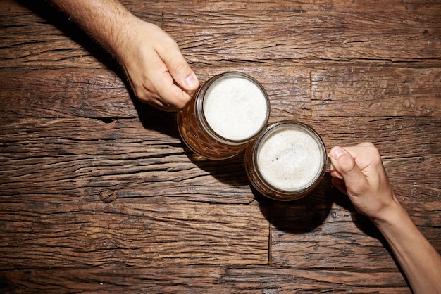 Foto männliche hände mit bierbecher auf einem alten holztisch