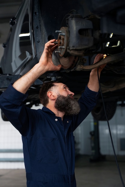 Männlicher Mechaniker, der in der Autowerkstatt am Auto arbeitet