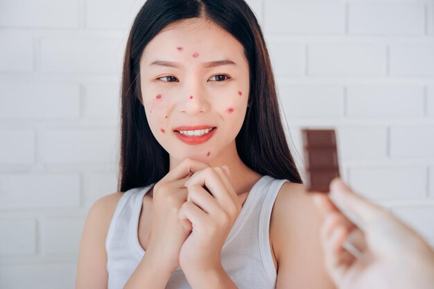 Foto mão cortada de pessoa dando barras de chocolate para uma jovem sorridente de pé contra a parede