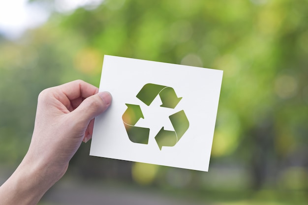 Foto mão segurando o papel branco com símbolo de reciclagem