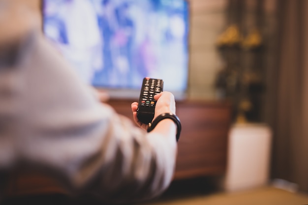 Mão usando o controle remoto para assistir TV.