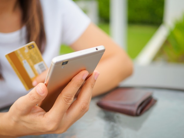 Mãos femininas, segurando, um, cartão crédito, e, usando, esperto, telefone, para, shopping online