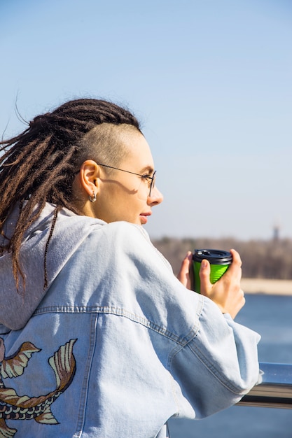 Menina bonita na moda moderna sozinha em um passeio de primavera pelo rio