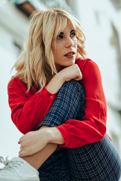 Menina loura com camisa vermelha que aprecia a vida ao ar livre.