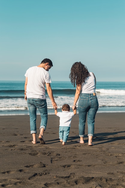 Menino bebê, segurando, pais, mãos, e, andar praia