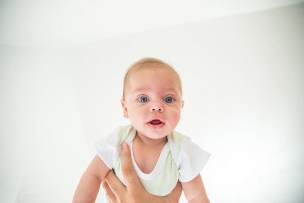 Menino de olhos azuis sendo levantado pelos braços do pai