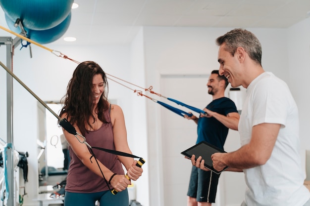 Menino e menina latinos fazendo exercícios para os braços com a ajuda de um personal trainer