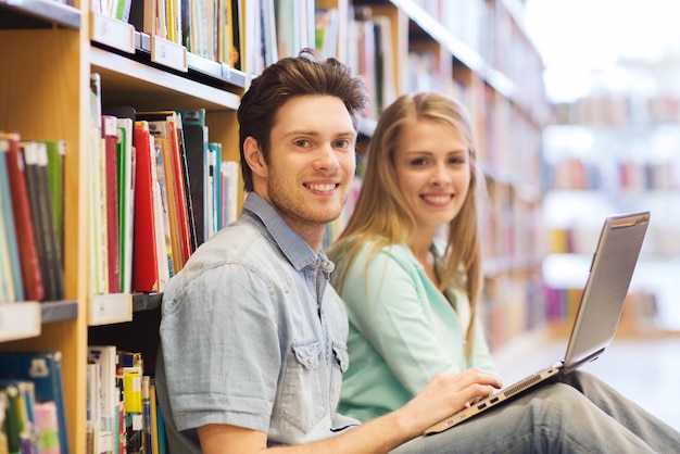 menschen, bildung, technologie und schulkonzept - glückliche schüler mit laptop-netzwerk in der bibliothek