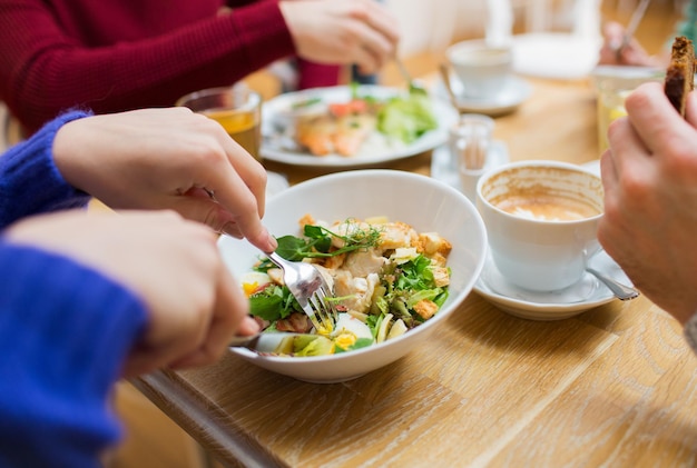 Foto menschen-, freizeit- und lebensmittelkonzept - schließen sie freunde zu abendessen und essen im restaurant