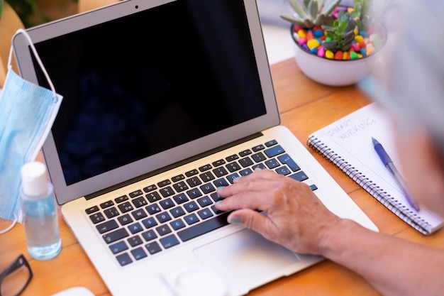 Mittelabschnitt einer Frau, die einen Laptop auf dem Tisch benutzt