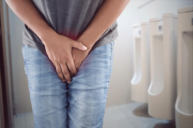 Foto mittelabschnitt eines mannes, der an urinalschmerzen im badezimmer leidet