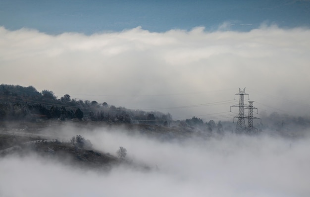 Montanhas nebulosas para fundo Pilão elétrico entre névoa e nuvens Floresta no inverno