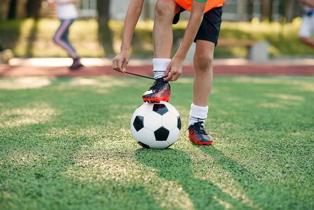 Foto müder fußballspieler im freiluftstadion, der den schnürsenkel an seinen trainingsstiefeln bindet