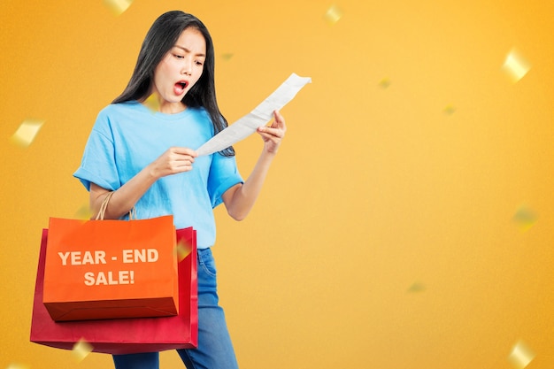 Foto mulher asiática com sacolas de compras chocada depois de fazer compras na venda de fim de ano. feliz ano novo 2021