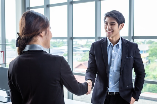 Foto mulher de negócios asiática e empresário apertando as mãos em no plano de fundo da sala de escritório após a assinatura do contrato ou acordo de cumprimento de aperto de mão, negócios expressaram confiança encorajar e casal bem sucedido