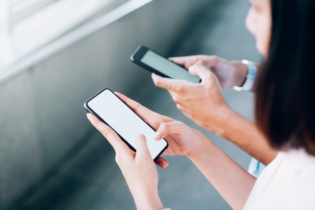 Mulher e homem segurando um smartphone, mock-se da tela em branco. usando o celular no estilo de vida. Tecnologia para o conceito de comunicação.