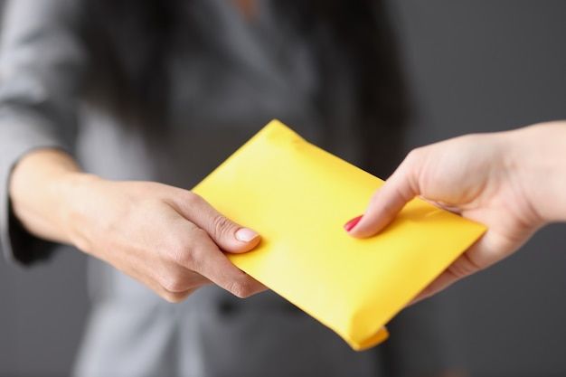 Mulher entrega envelope amarelo fechado com dinheiro para fraude de funcionário e prêmios em envelopes