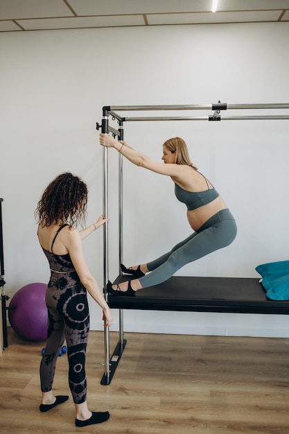 Mulher grávida pilates reformer roll up cadillac exercício com personal trainer