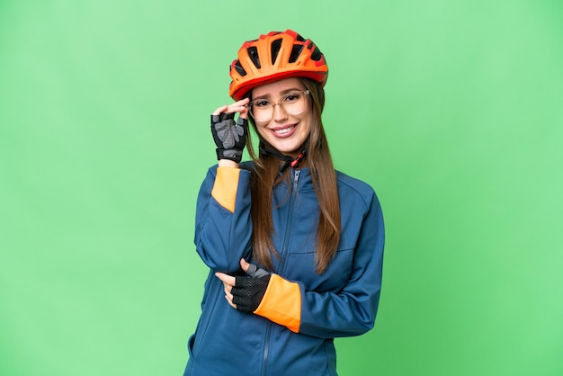 Mulher jovem ciclista sobre fundo croma chave isolado com óculos e feliz