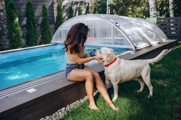 Mulher relaxando perto da piscina com cachorro fofo