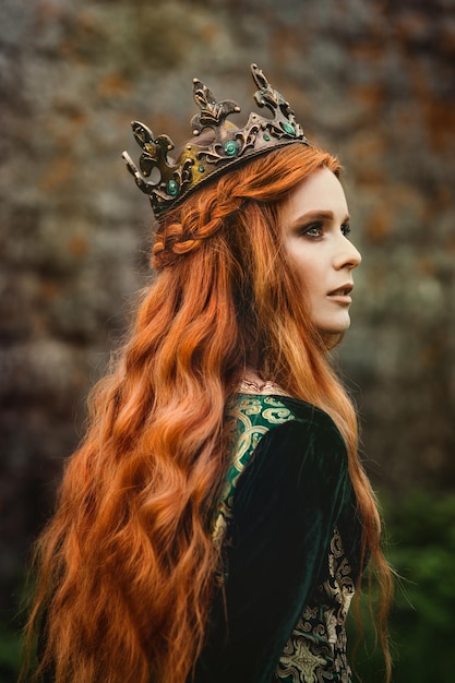 Mulher ruiva em um vestido verde medieval perto do castelo