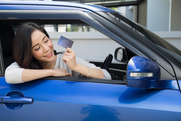 Foto mulher sorridente mostrando cartão de crédito enquanto está sentada no carro