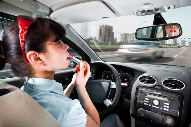 mulheres compõem lábios ao volante do carro