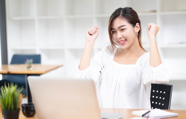 Foto mulheres de negócios asiáticas estão encantadas e felizes com o trabalho que fazem em seu laptop e tomando notas no escritório