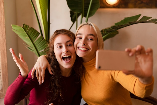 Mulheres sorridente em tiro médio tirando selfie