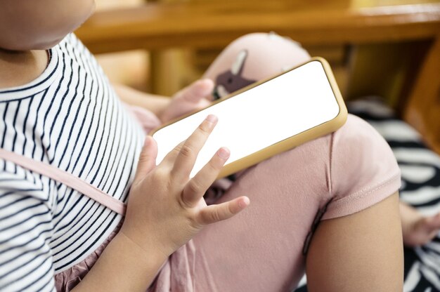 Foto nahaufnahme des asiatischen kleinen mädchenfingers, der auf dem smartphone im haus berührt