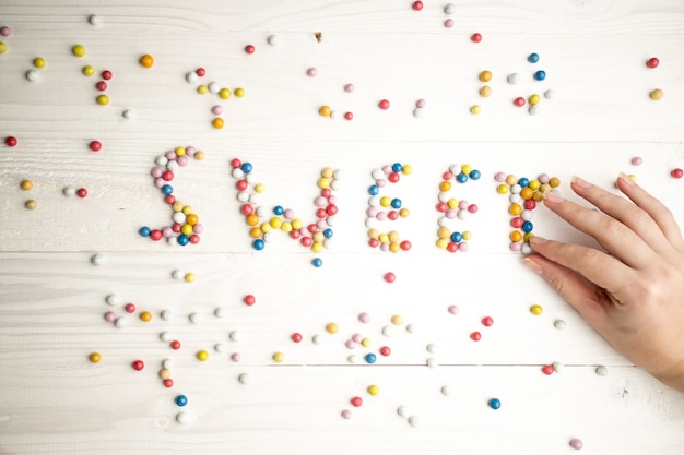 Foto nahaufnahmefoto einer frau, die aus bunten bonbons das wort süß macht