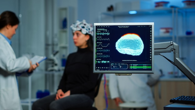 Foto neurologe arzt analysiert das nervensystem mit dem eeg-headset, das das gehirn der frau scannt. wissenschaftler forscher, der high-tech verwendet, um neurologische innovationen zu entwickeln und nebenwirkungen auf dem bildschirm zu überwachen